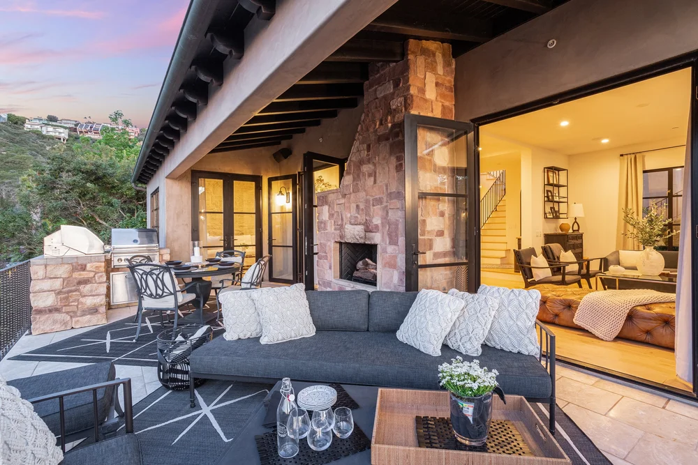 Outdoor stone fireplace lounge with grill at dusk