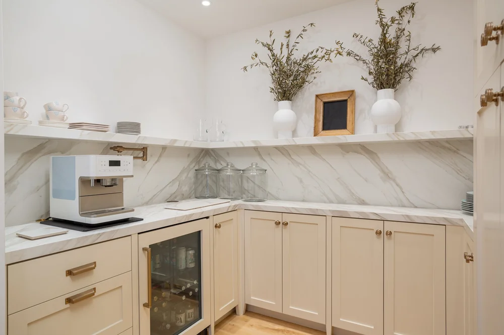 Butler's pantry with marble backsplash and brass fixtures
